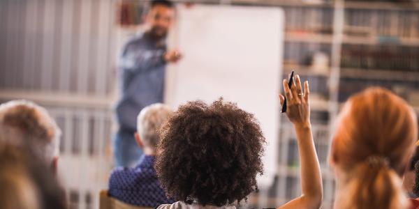 Woman raising her hand in a learning atmosphere.