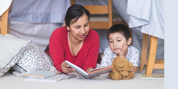 Mother and son reading a book on the floor of a child's room
