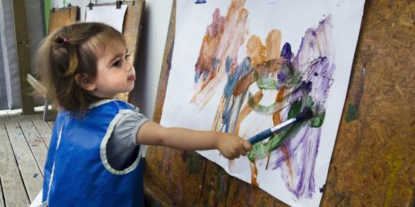Toddler in smock painting on easel