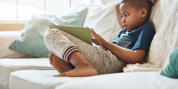 young preschool boy sitting on a couch reading