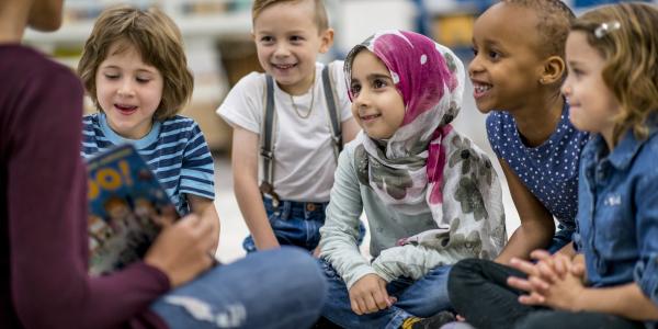 a teacher reading a book to a group of children