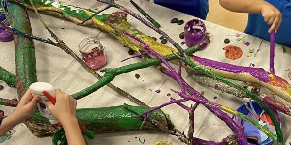 children painting tree branches in a classroom