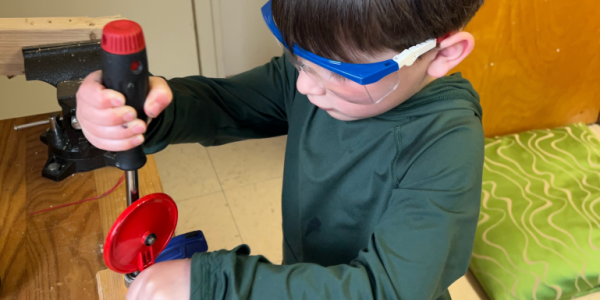 a young child with safety goggles using some tools