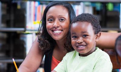 Female teacher and preschool boy sitting at a table in a classroom