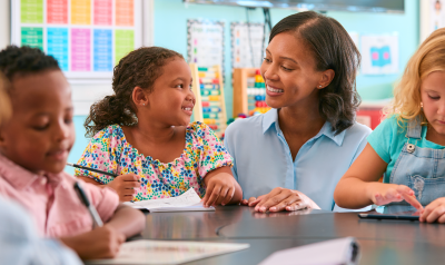 a teacher talking with students in a classroom