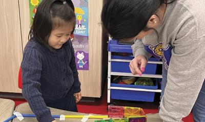 a young girl and a teacher playing with a craft