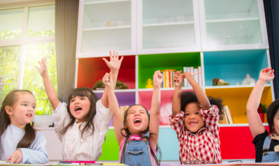 children celebrating in the classroom with their hands up