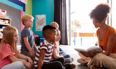 a teacher reading a book to children