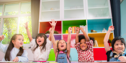 children celebrating in the classroom with their hands up