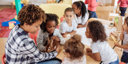 a teacher and children petting a bunny in a classroom