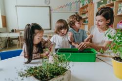 a teacher and students observing plants in a tray of soil